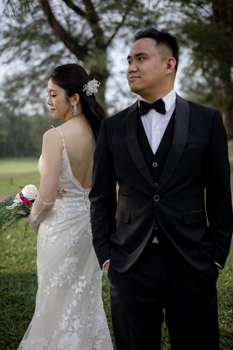 Caroline and Ying Lin standing back-to-back outdoors in wedding attire